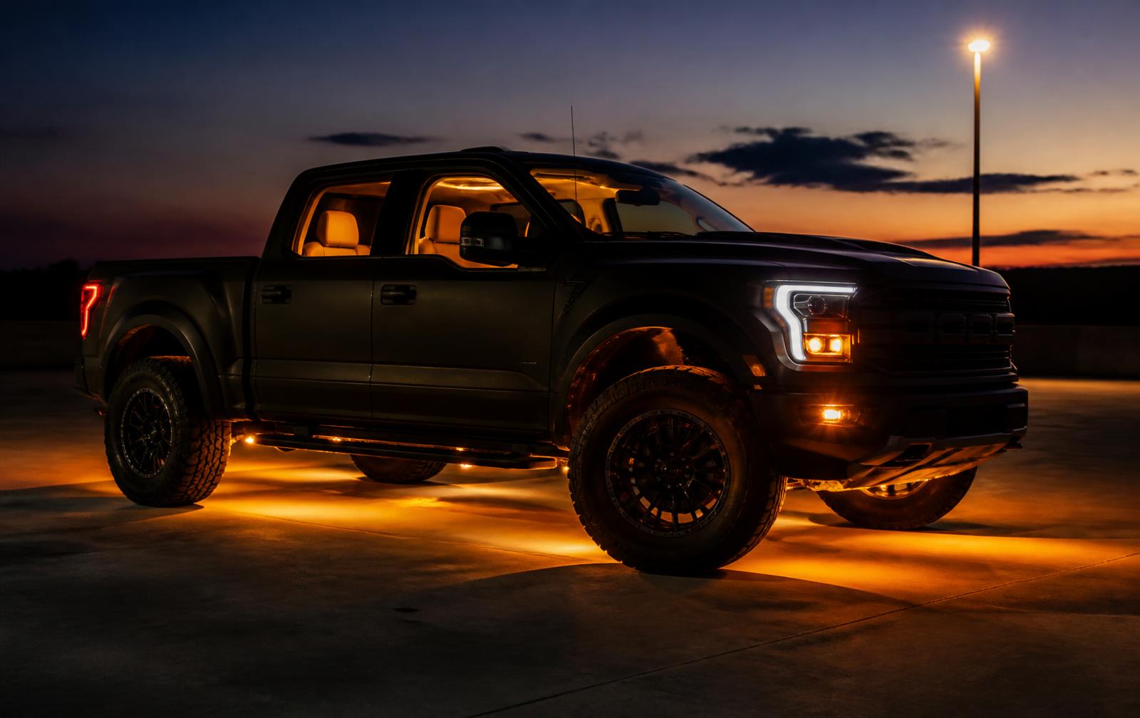 Truck with custom amber underglow lighting at dusk